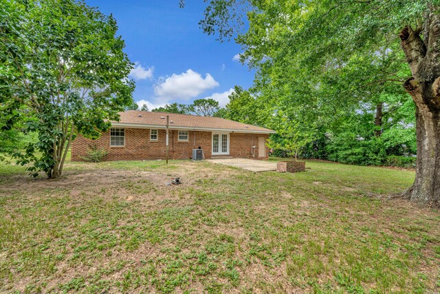 rear view of property featuring a lawn, central AC, and a patio