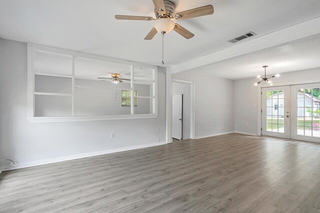 unfurnished living room with french doors, ceiling fan with notable chandelier, a textured ceiling, and wood-type flooring