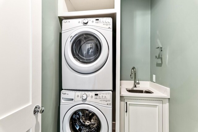 clothes washing area featuring cabinets, stacked washing maching and dryer, and sink