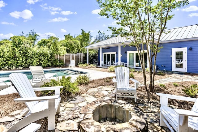 view of patio featuring a fenced in pool, french doors, ceiling fan, and an outdoor fire pit