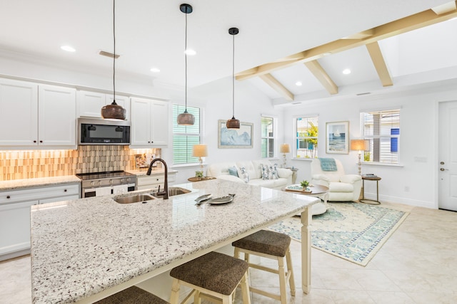 kitchen with sink, lofted ceiling with beams, appliances with stainless steel finishes, a kitchen breakfast bar, and backsplash