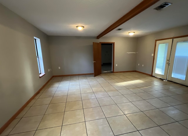 tiled spare room featuring french doors, plenty of natural light, and beam ceiling