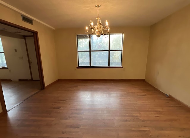 empty room featuring hardwood / wood-style flooring and an inviting chandelier