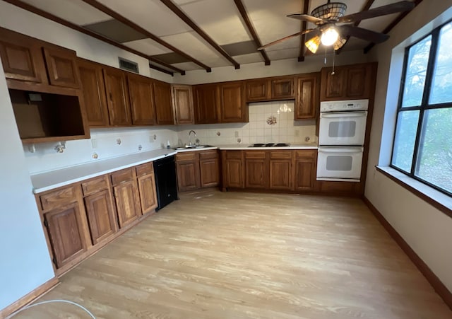 kitchen with double oven, ceiling fan, tasteful backsplash, beamed ceiling, and light wood-type flooring