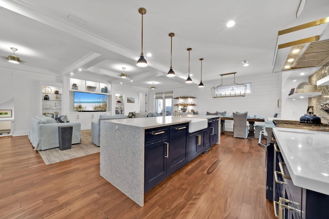 kitchen with blue cabinets, decorative light fixtures, built in features, ceiling fan, and a large island