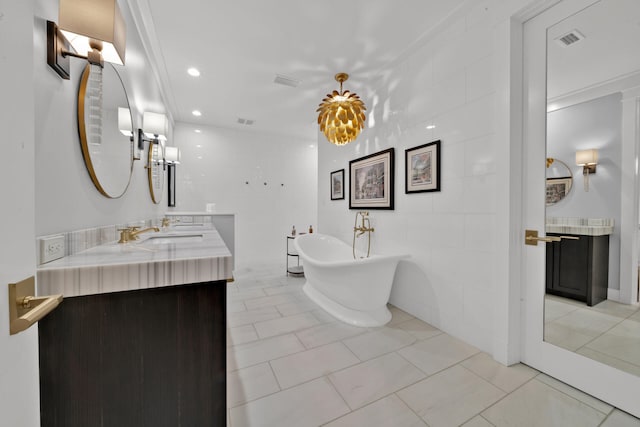 bathroom featuring tile walls, tile patterned flooring, vanity, a washtub, and crown molding