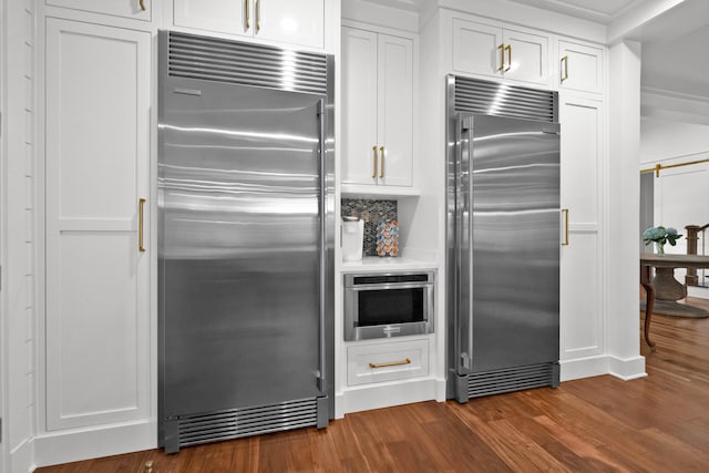 kitchen with tasteful backsplash, white cabinetry, dark hardwood / wood-style flooring, stainless steel appliances, and a barn door