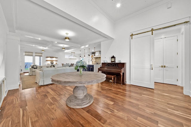 dining room with crown molding, a barn door, and light hardwood / wood-style flooring