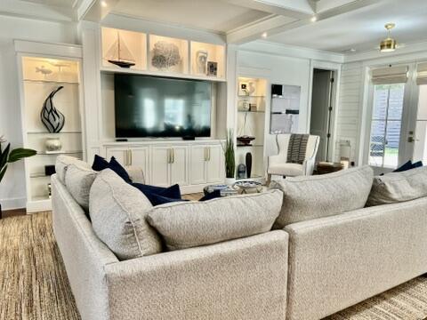 living room with coffered ceiling, hardwood / wood-style floors, beam ceiling, and built in shelves