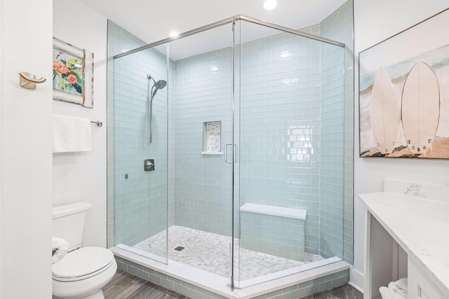 bathroom featuring an enclosed shower, vanity, toilet, and hardwood / wood-style floors