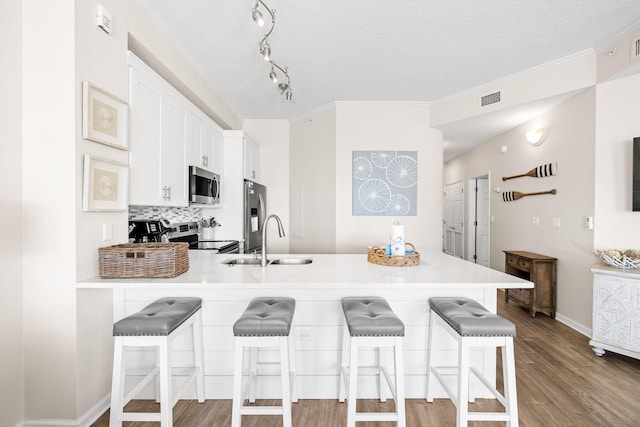 kitchen with white cabinets, a breakfast bar, kitchen peninsula, and stainless steel appliances