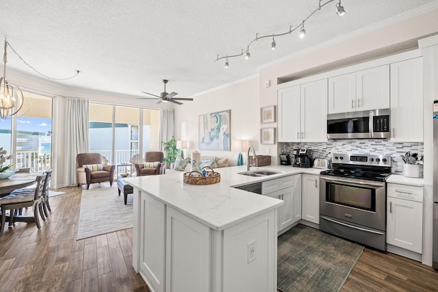 kitchen with stainless steel appliances, white cabinets, kitchen peninsula, and sink