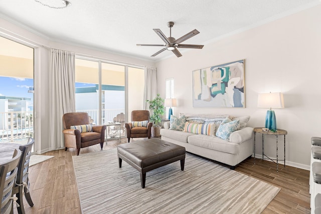 living room featuring ceiling fan, a wealth of natural light, ornamental molding, and a textured ceiling