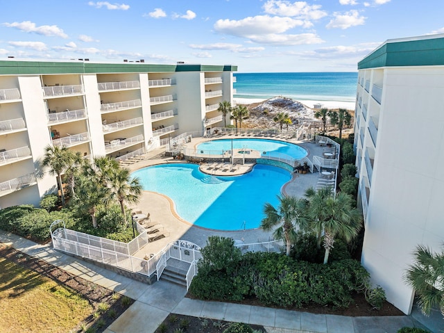 view of pool with a patio area, a water view, and a view of the beach