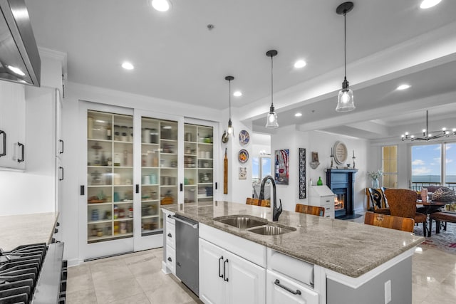 kitchen featuring white cabinetry, dishwasher, a kitchen island with sink, pendant lighting, and sink