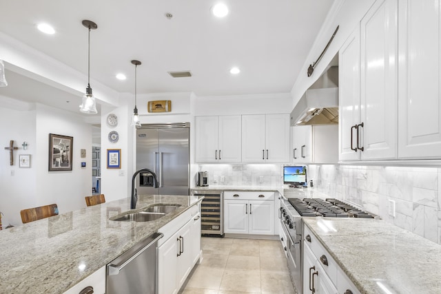 kitchen with tasteful backsplash, wall chimney range hood, sink, white cabinetry, and premium appliances