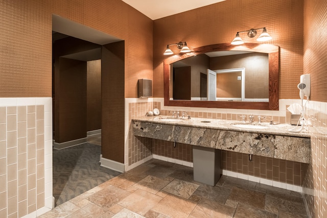 bathroom featuring double vanity, decorative backsplash, tile walls, and tile patterned flooring