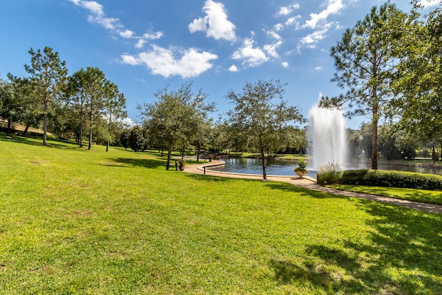 view of home's community with a water view and a lawn