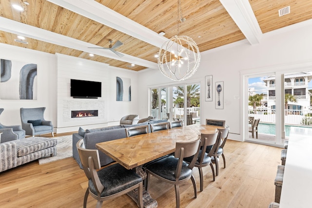 dining space featuring beamed ceiling, light hardwood / wood-style floors, a fireplace, and wood ceiling