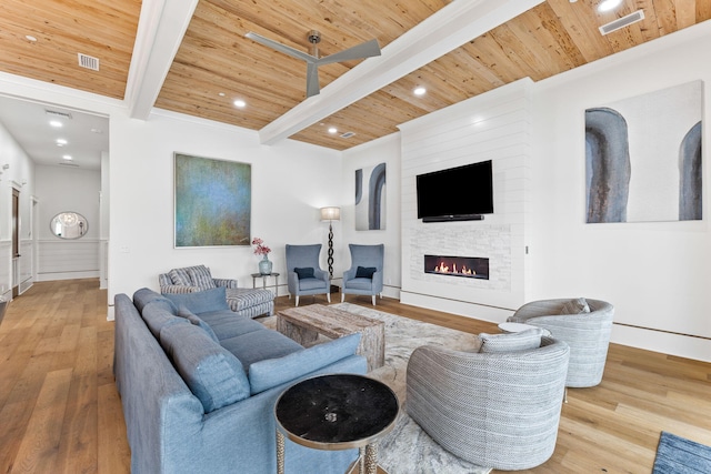 living room featuring wood ceiling, a stone fireplace, beam ceiling, and light wood-type flooring