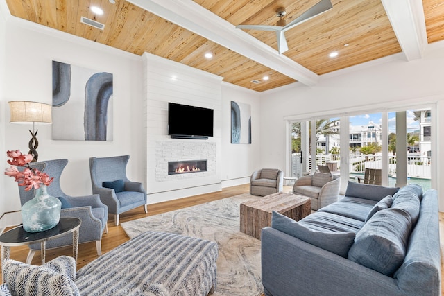 living room featuring beamed ceiling, light hardwood / wood-style floors, a fireplace, and wood ceiling