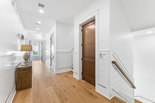 hall featuring lofted ceiling and light hardwood / wood-style flooring