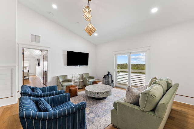 living room with high vaulted ceiling and light wood-type flooring