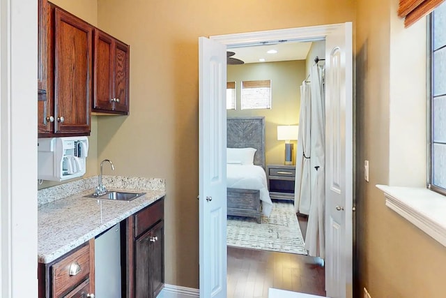 interior space with sink, dark hardwood / wood-style floors, and light stone counters