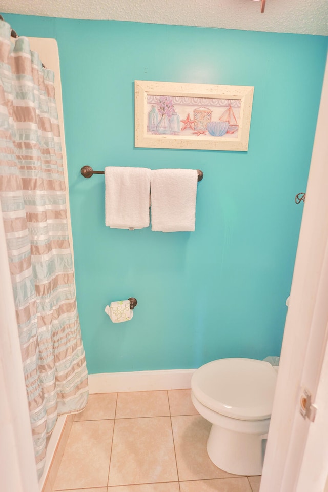 bathroom featuring a textured ceiling, toilet, and tile flooring