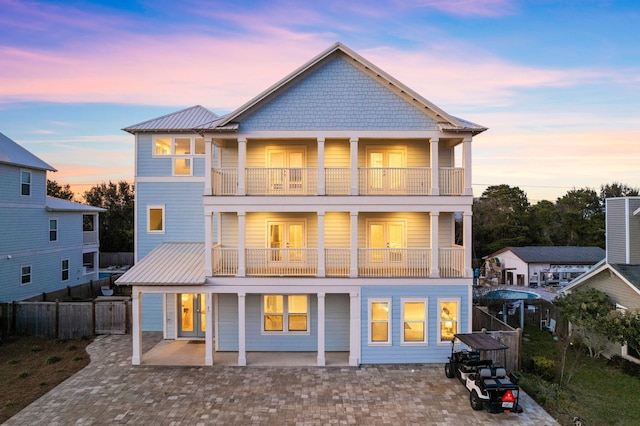 back house at dusk with a balcony and a patio area