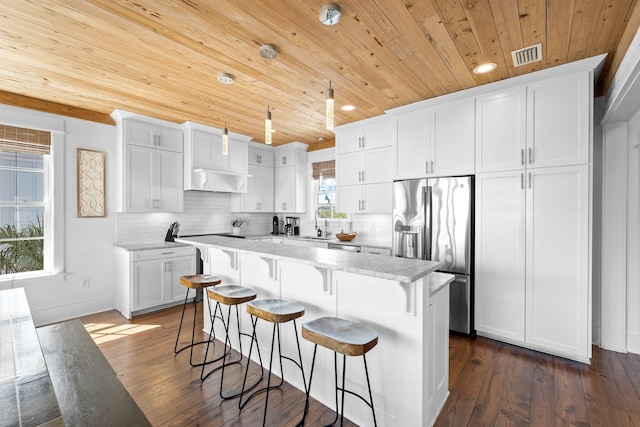 kitchen with tasteful backsplash, white cabinetry, dark wood-type flooring, stainless steel refrigerator with ice dispenser, and a wealth of natural light