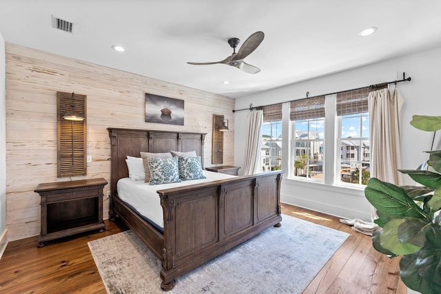 bedroom with wood-type flooring, ceiling fan, and wooden walls