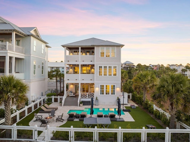 back house at dusk with a patio and a balcony