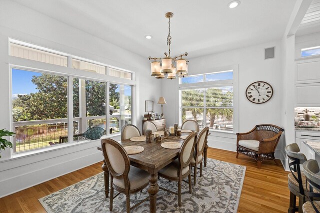 dining room with plenty of natural light, light hardwood / wood-style floors, and a notable chandelier