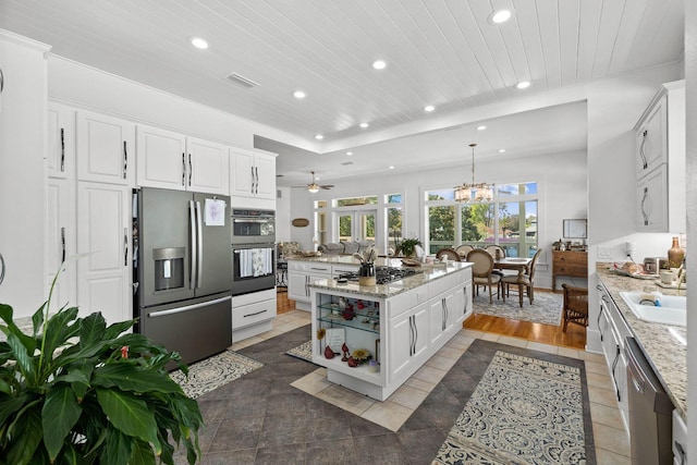 kitchen featuring a kitchen island, ceiling fan with notable chandelier, stainless steel appliances, and white cabinetry