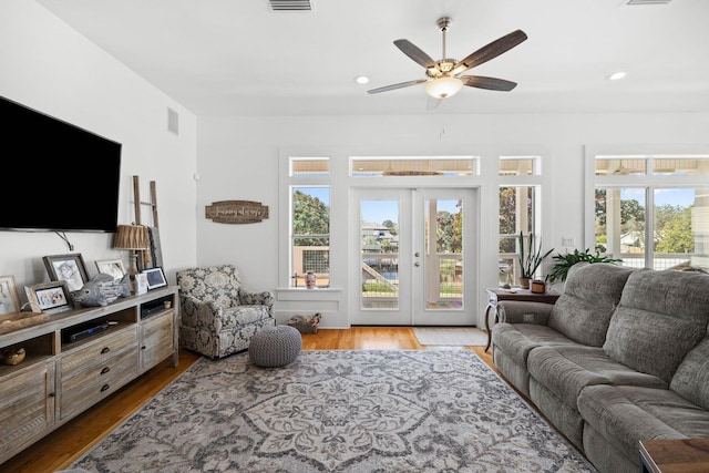 living room featuring a wealth of natural light, light hardwood / wood-style floors, ceiling fan, and french doors