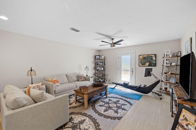 living room with ceiling fan and a textured ceiling