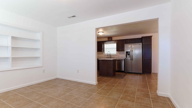 kitchen featuring light stone counters, appliances with stainless steel finishes, dark brown cabinets, sink, and light tile floors