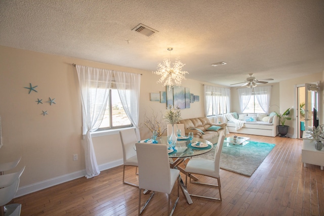 dining room with ceiling fan with notable chandelier, a textured ceiling, and hardwood / wood-style floors