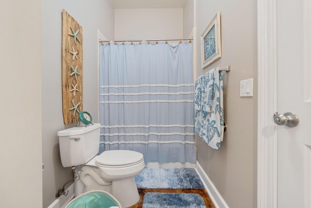 bathroom featuring toilet, a shower with curtain, and hardwood / wood-style flooring