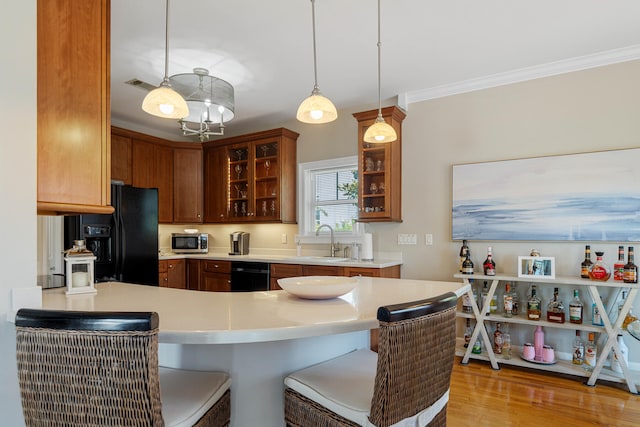 kitchen with pendant lighting, a kitchen breakfast bar, black refrigerator with ice dispenser, and sink