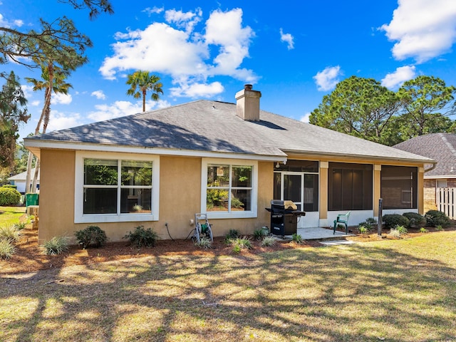 rear view of house featuring a lawn and a sunroom