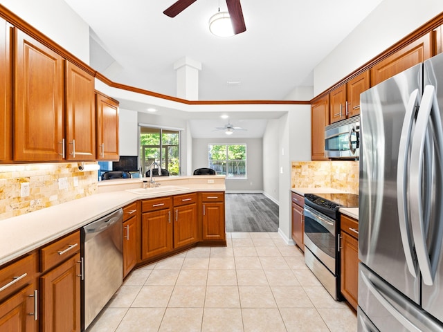 kitchen featuring kitchen peninsula, sink, ceiling fan, appliances with stainless steel finishes, and light tile patterned flooring