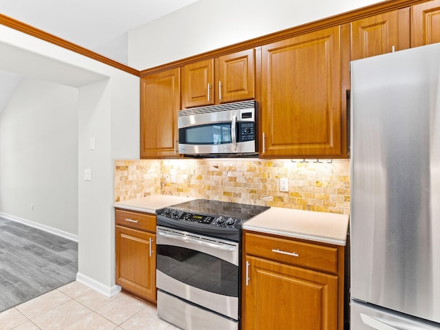 kitchen with light tile patterned flooring, appliances with stainless steel finishes, and decorative backsplash