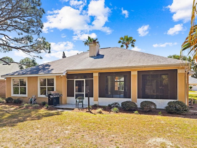 back of house featuring a sunroom and a lawn