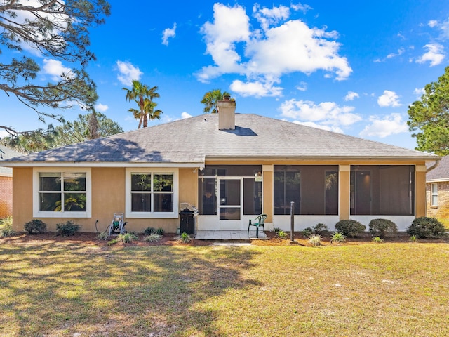 rear view of house with a yard and a sunroom