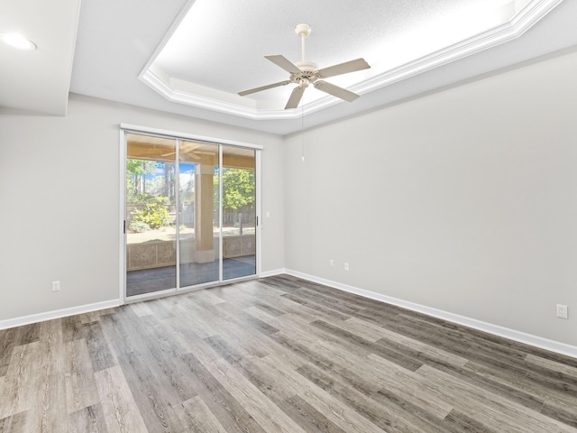 spare room featuring a tray ceiling, hardwood / wood-style flooring, a textured ceiling, and ceiling fan