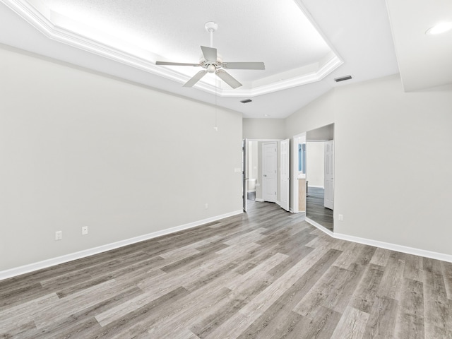 unfurnished bedroom with a tray ceiling, ceiling fan, and light wood-type flooring