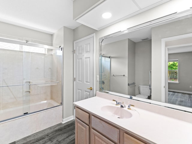 full bathroom featuring hardwood / wood-style flooring, toilet, vanity, and enclosed tub / shower combo