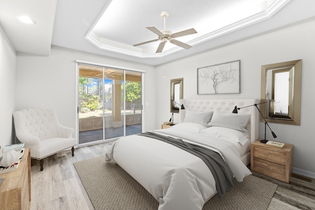 bedroom featuring a raised ceiling, light hardwood / wood-style floors, ceiling fan, and access to exterior